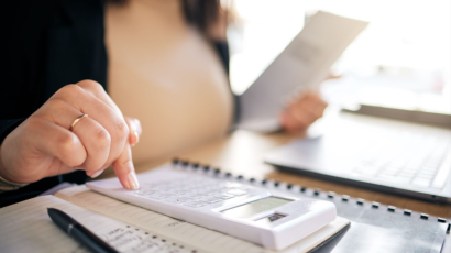 Closeup on a woman using a calculator and notebooks to bookkeep.