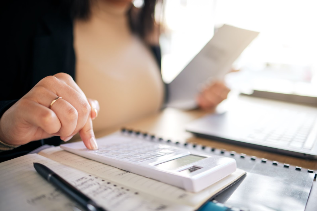 Closeup on a woman using a calculator and notebooks to bookkeep.