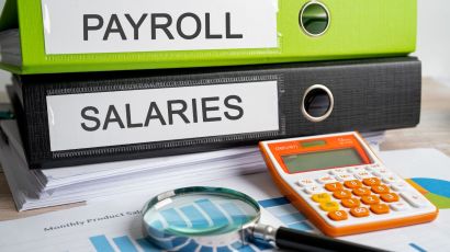 Business payroll and salary documents in binders alongside financial reports with charts and data analysis