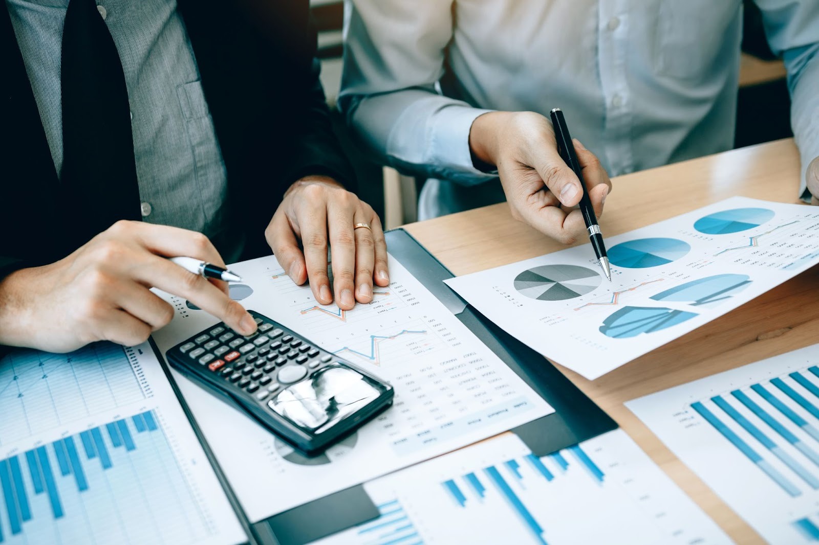 Two accounting professionals review company finances with a calculator and a chart