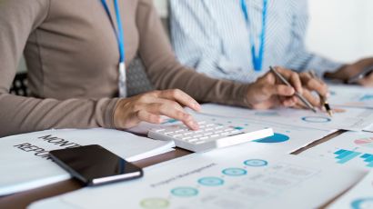 Accounting service team collaborating while reviewing a monthly financial report with graphs and charts